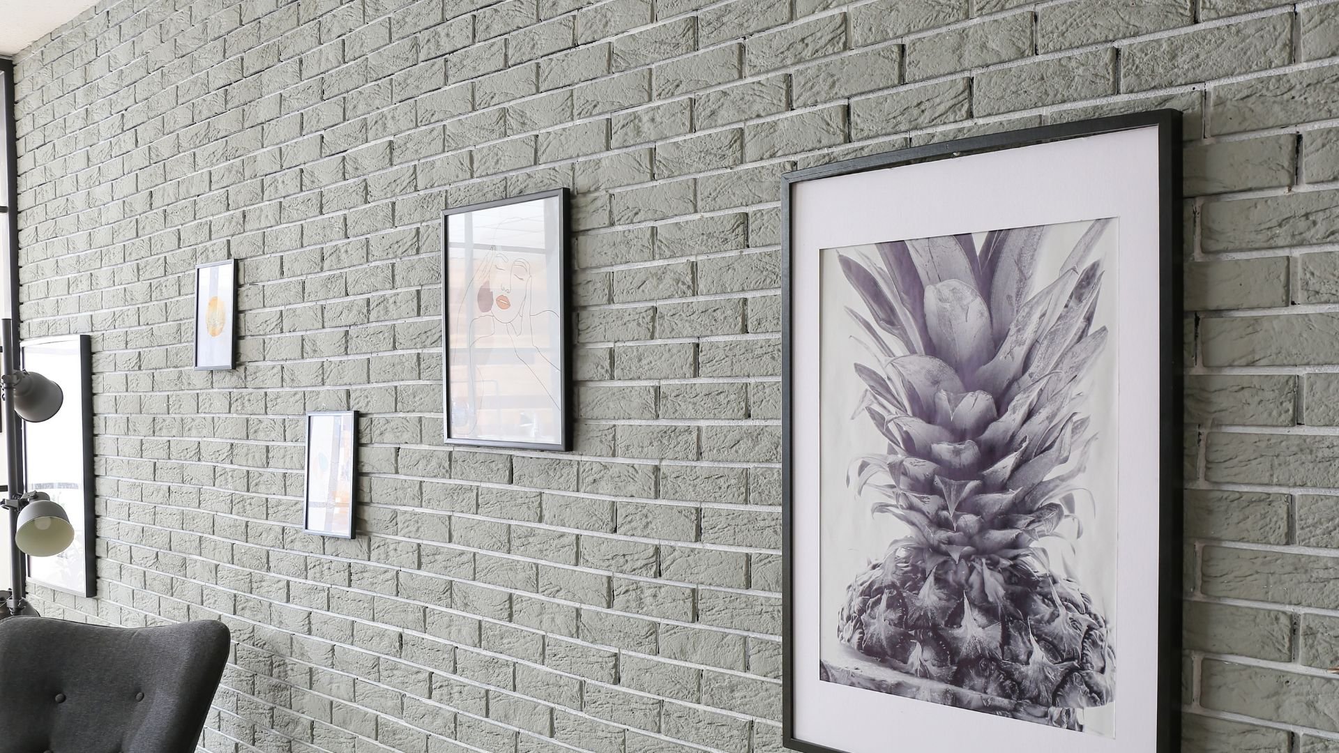 Black and white framed pineapple artwork on textured brick wall